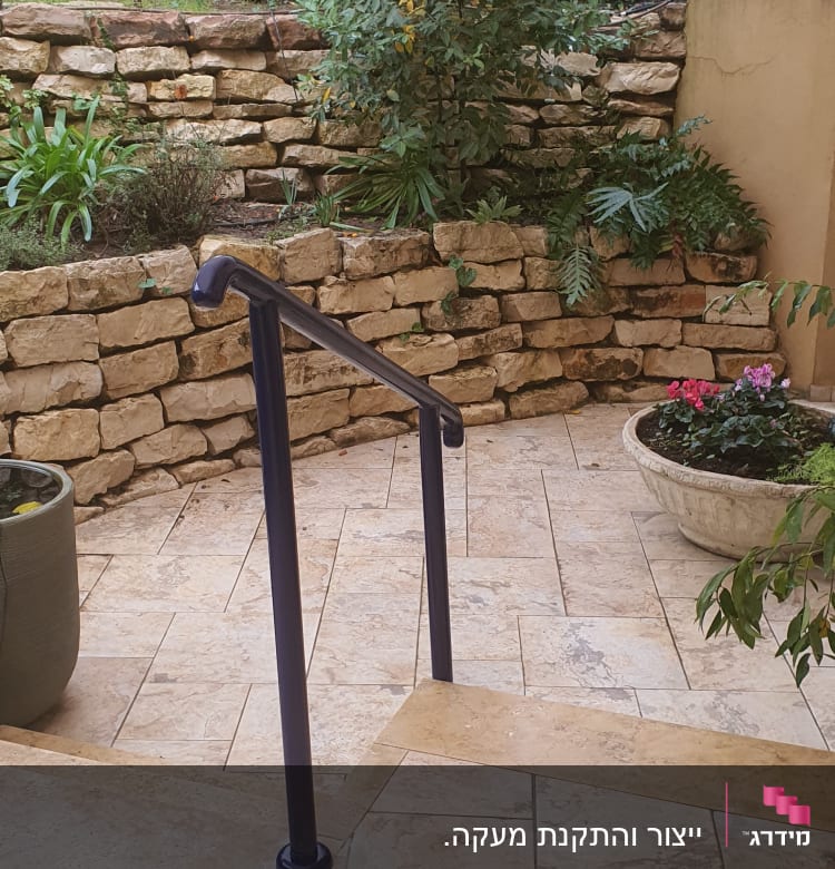 מעקה מתכת כחול על רצפת אבן בגינה